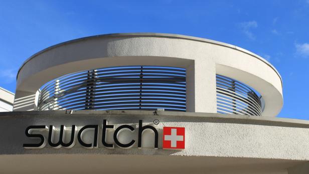 Das Logo von Swatch an einem Gebäude unter blauem Himmel.