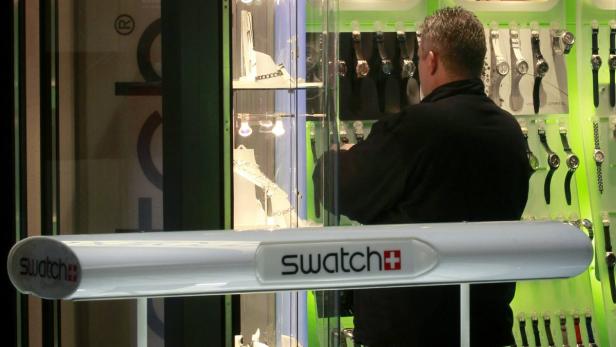 Ein Mann steht vor einem Schaufenster von Swatch und betrachtet die Uhren.