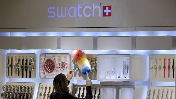 Eine Frau staubt in einem Swatch-Geschäft die Auslage mit Uhren ab.