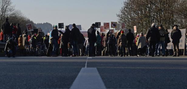 Eine Menschenmenge steht auf einer Straße und hält Schilder hoch.