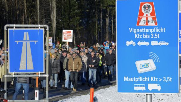 Eine Menschenmenge demonstriert neben Schildern zur Vignettenpflicht in Österreich.