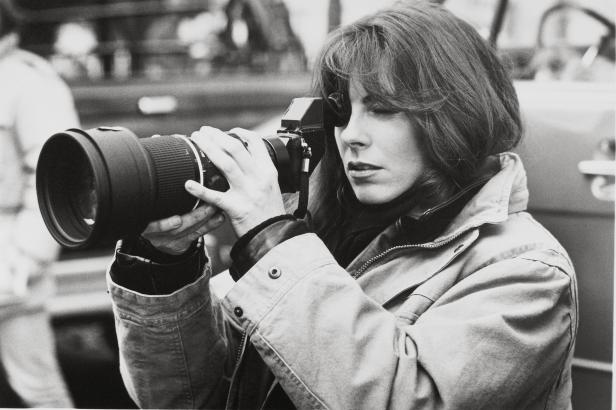 Eine Frau mit einer professionellen Kamera mit Teleobjektiv fotografiert.
