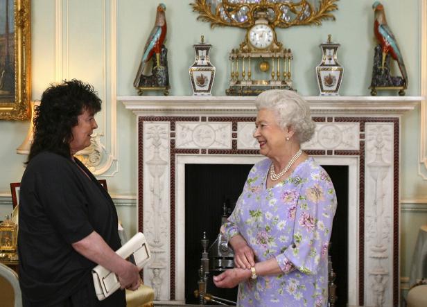 Königin Elisabeth II. unterhält sich mit einer Frau in einem eleganten Raum.