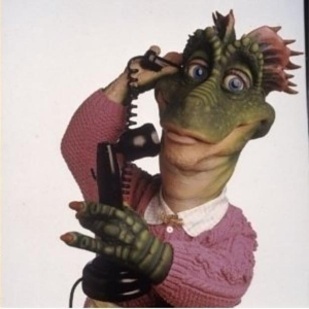 Eine Dinosaurier-Puppe in einem rosa Pullover telefoniert.