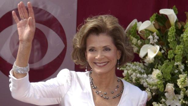 Jessica Walter winkt vor einem Blumenarrangement und einem CBS-Logo.