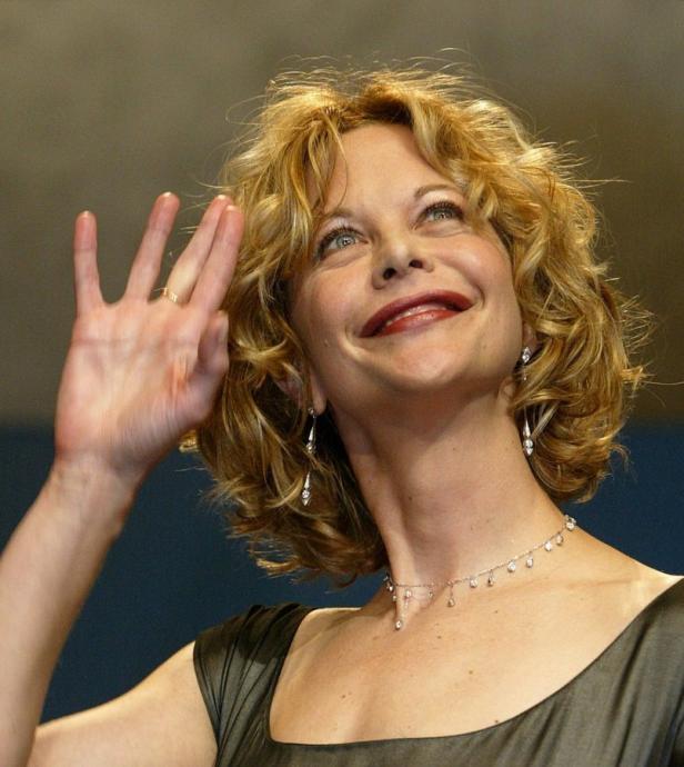 Meg Ryan lächelt und winkt mit der Hand.