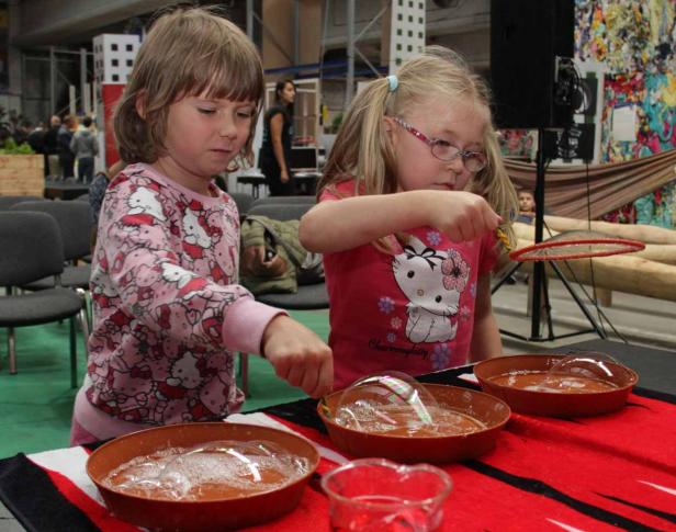 Zwei Mädchen machen Seifenblasen mit Schalen und einem Ring.