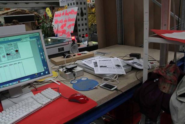 Ein Schreibtisch mit einem Computer, Papieren und verschiedenen Gegenständen darauf.