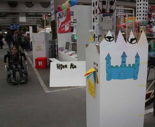 Ein Mädchen im Rollstuhl fährt durch einen Raum mit Installationen und Dekorationen.