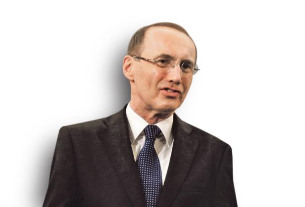 Ein Mann mit Brille und dunklem Anzug vor einem weißen Hintergrund.