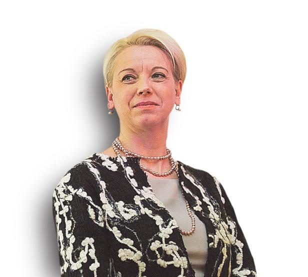 Eine Frau mit blonden, kurzen Haaren und einer Perlenkette lächelt.