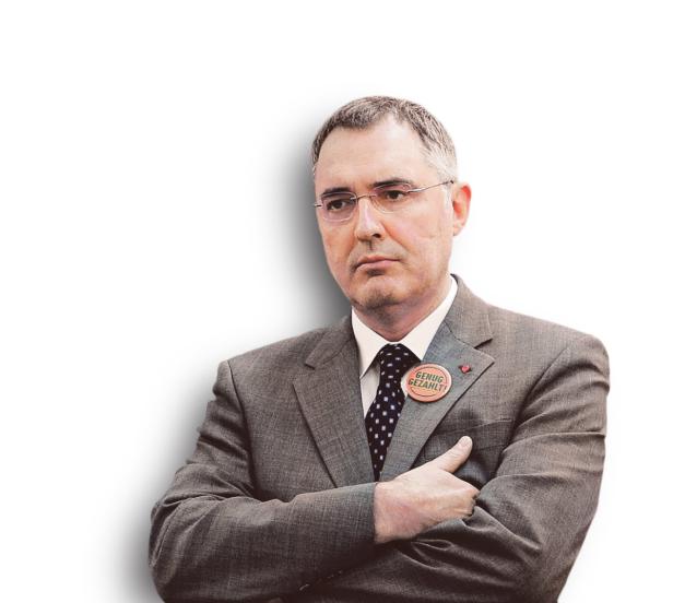 Ein Mann mit Brille und Anzug trägt einen Button mit der Aufschrift „Genug gezahlt!“.