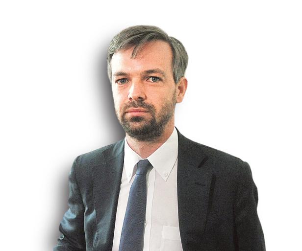 Ein Mann mit Bart und Anzug blickt in die Kamera.