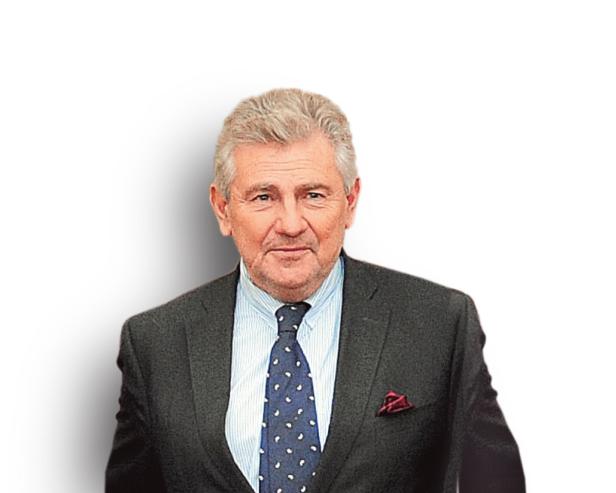 Ein älterer Mann mit grauem Haar trägt einen Anzug und eine Krawatte.