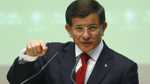 Ahmet Davutoğlu bei einer Rede vor Mikrofonen.