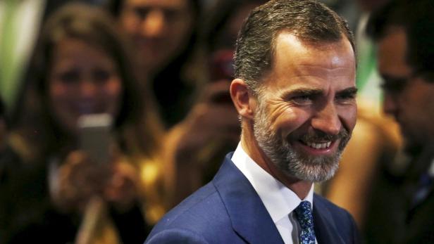 König Felipe VI. lächelt in die Kamera, im Hintergrund eine Menschenmenge.