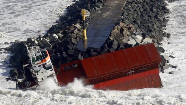 Ein Schiff ist bei stürmischer See an einem Wellenbrecher gestrandet.
