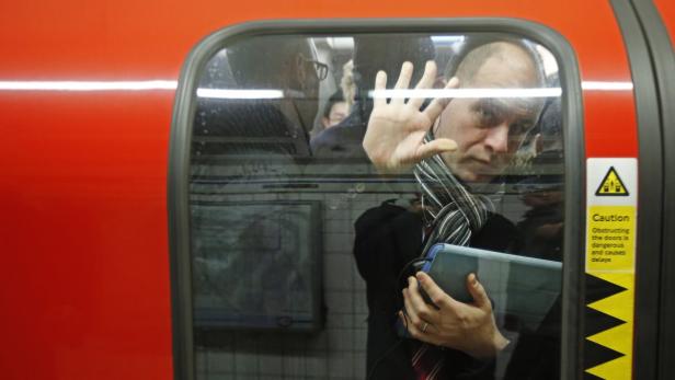 Ein Mann mit Tablet steht in einer U-Bahn und hält seine Hand an die Tür.