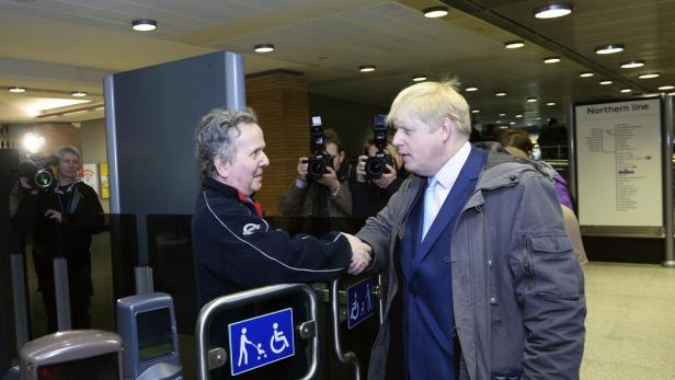 Boris Johnson schüttelt einem Mann an einem U-Bahn-Eingang die Hand.