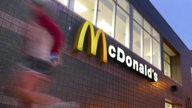 Ein McDonald's Restaurant mit dem goldenen M und einer verschwommenen Person im Vordergrund.