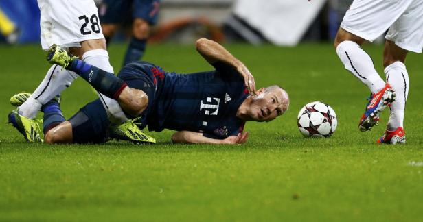 Ein Fußballspieler liegt nach einem Zweikampf auf dem Rasen.
