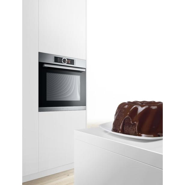 Ein Schokoladenkuchen steht auf einer weißen Oberfläche neben einem modernen Ofen.