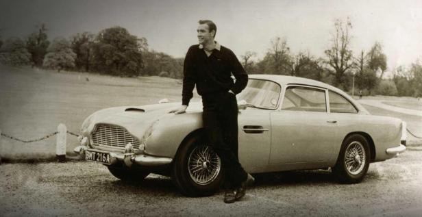 Sean Connery posiert an einem Aston Martin DB5.