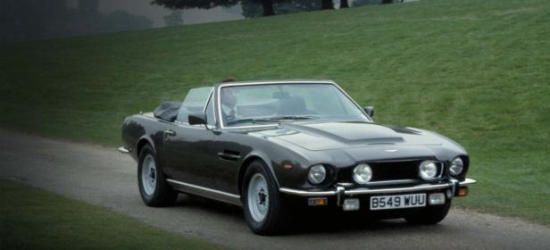 Ein grauer Aston Martin Volante fährt auf einer Landstraße.