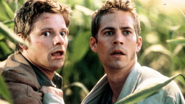 Zwei verängstigte Männer, möglicherweise Ryan Reynolds und Paul Walker, stehen in einem Feld.