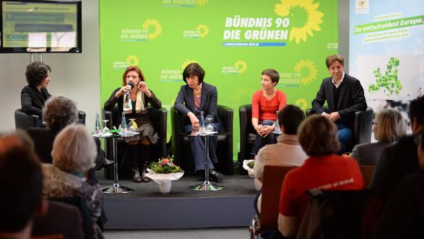 Eine Podiumsdiskussion der Grünen mit mehreren Personen vor einem grünen Banner.
