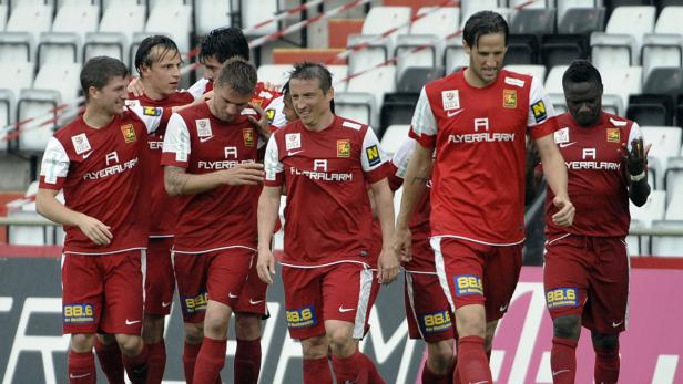 Eine Gruppe Fußballspieler in roten Trikots steht auf dem Spielfeld.