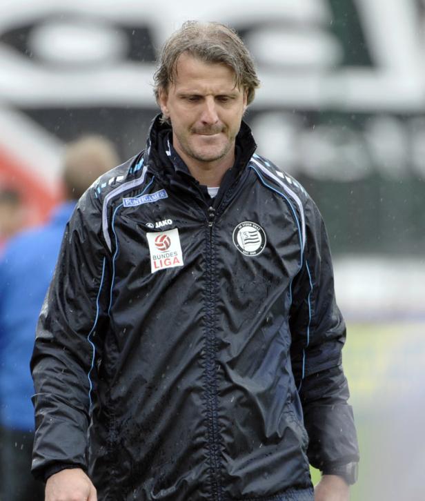 Ein Mann in einer Jacke des SK Sturm Graz steht im Regen.