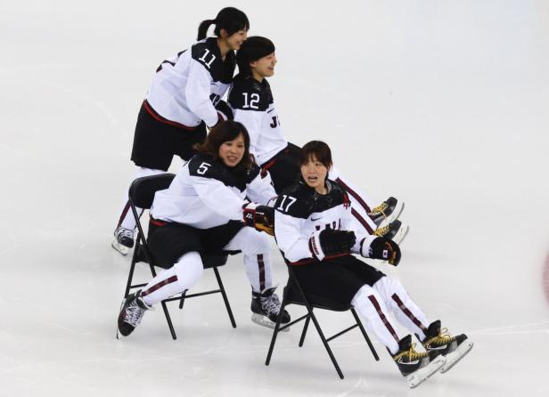 Vier japanische Eishockeyspielerinnen sitzen auf Stühlen auf dem Eis.