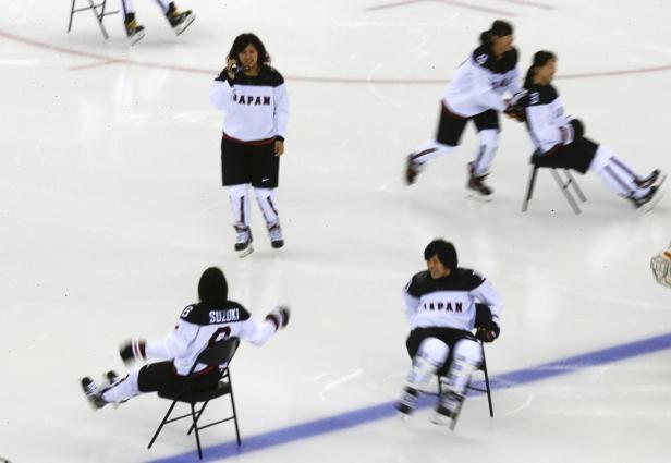 Mitglieder des japanischen Eishockeyteams sitzen auf Stühlen auf dem Eis.