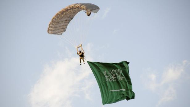 Ein Fallschirmspringer mit der Flagge Saudi-Arabiens am Himmel.