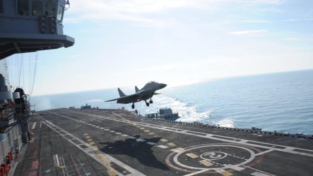 Ein Kampfjet landet auf einem Flugzeugträger auf offener See.