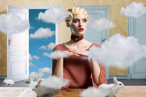 Eine Frau im Retro-Stil posiert vor Türen und Wolken, umgeben von weißen Kaninchen.