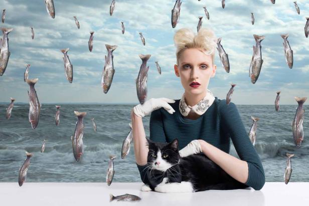 Eine Frau mit Katze vor einem Hintergrund mit Fischen und Meer.