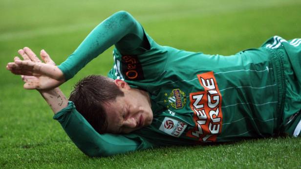 Ein Fußballspieler in grüner Spielkleidung liegt verletzt auf dem Rasen.