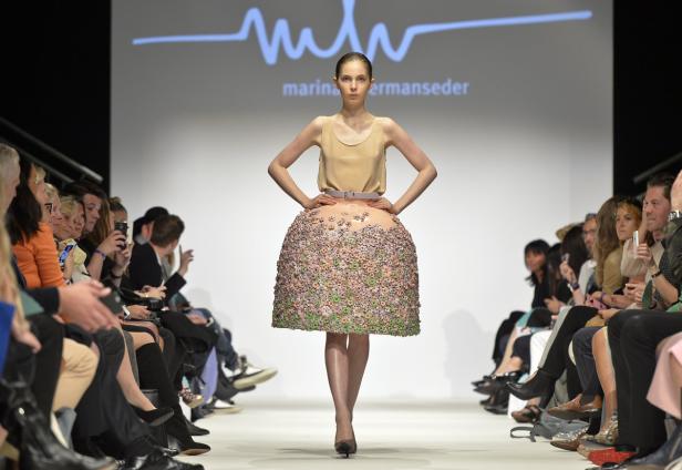 Ein Model präsentiert eine extravagante, blumenbesetzte Rockkreation von Marina Hoermanseder auf dem Laufsteg.