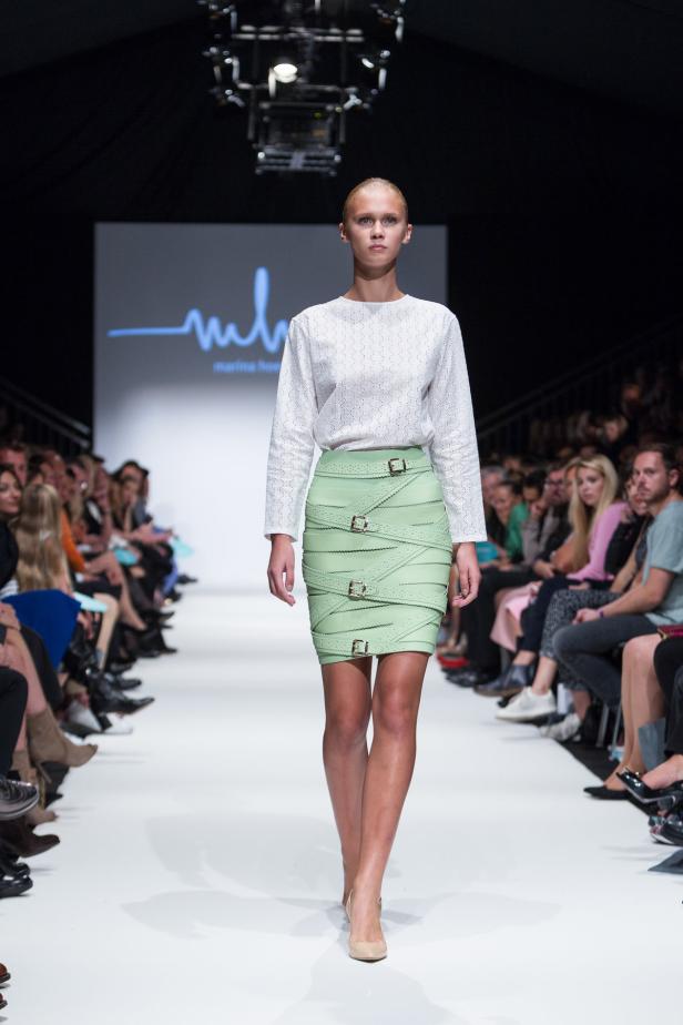 Ein Model präsentiert eine grüne Minirock-Kreation auf dem Laufsteg.
