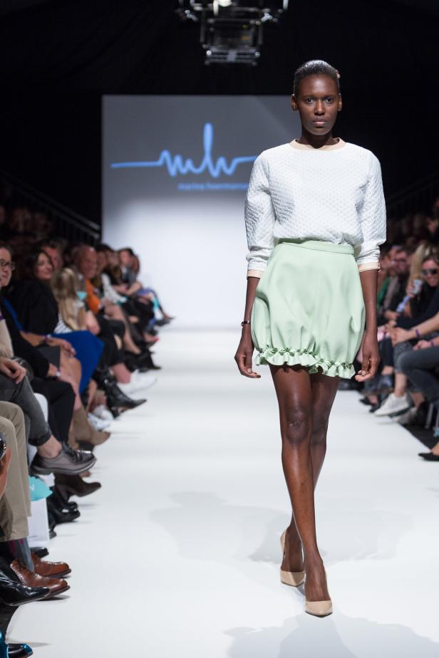 Eine dunkelhäutige Frau präsentiert ein Outfit auf einem Laufsteg.