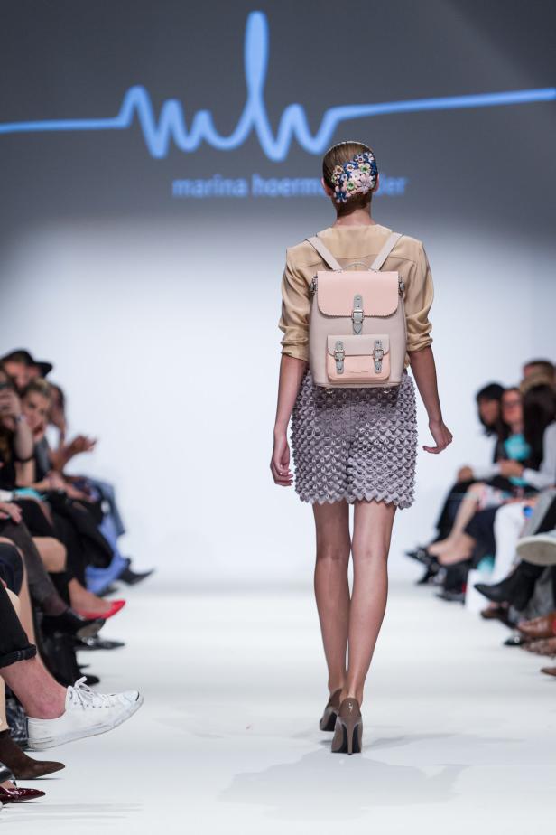 Eine Frau mit einem rosa Rucksack läuft auf einem Laufsteg.