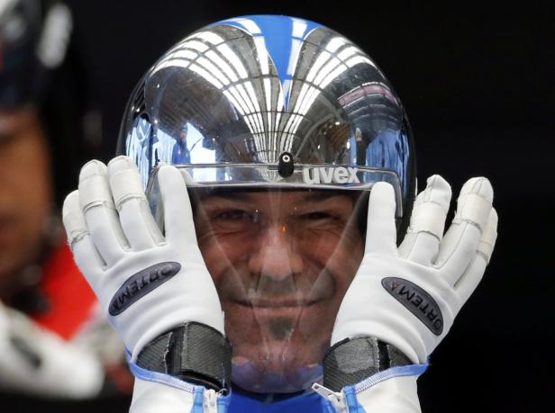 Ein Rennfahrer mit Helm und Visier lächelt in die Kamera.