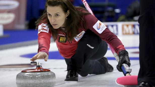 Eine Curlingspielerin kurz vor dem Loslassen des Steins.