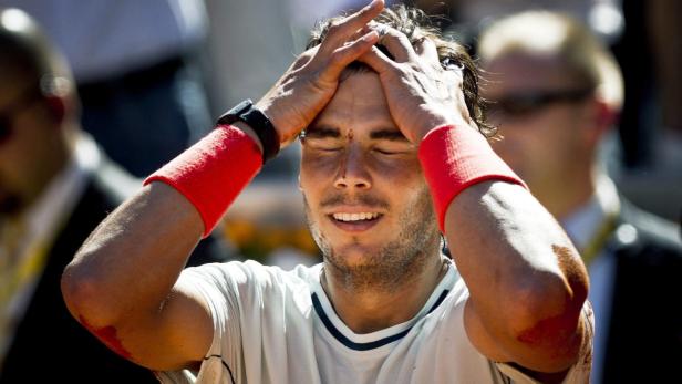 Ein Tennisspieler mit roten Schweißbändern hält sich frustriert den Kopf.