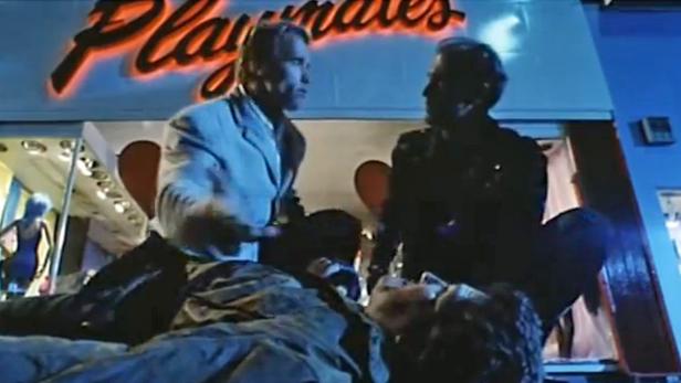 Arnold Schwarzenegger steht vor einem Nachtclub namens „Playmates“.