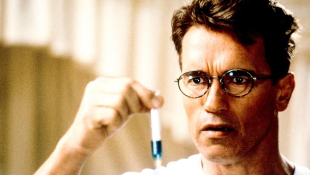 Arnold Schwarzenegger als Dr. Alex Hesse hält in „Junior“ eine Spritze mit einer blauen Flüssigkeit.