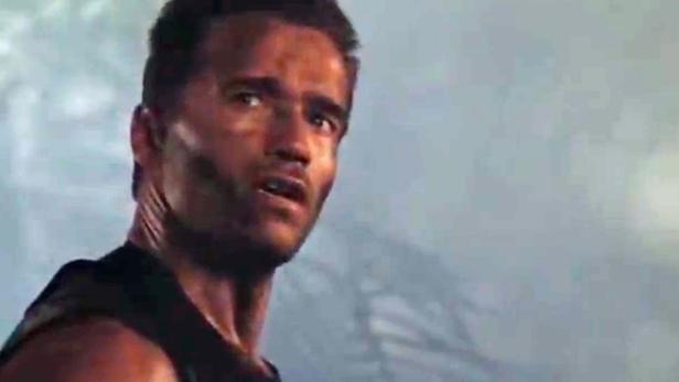 Arnold Schwarzenegger blickt in einer Szene aus dem Film „Predator“ besorgt zur Seite.