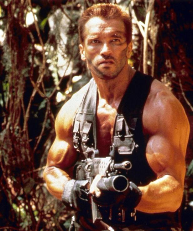 Arnold Schwarzenegger als Major Alan „Dutch“ Schaefer im Film „Predator“ mit einer Waffe.